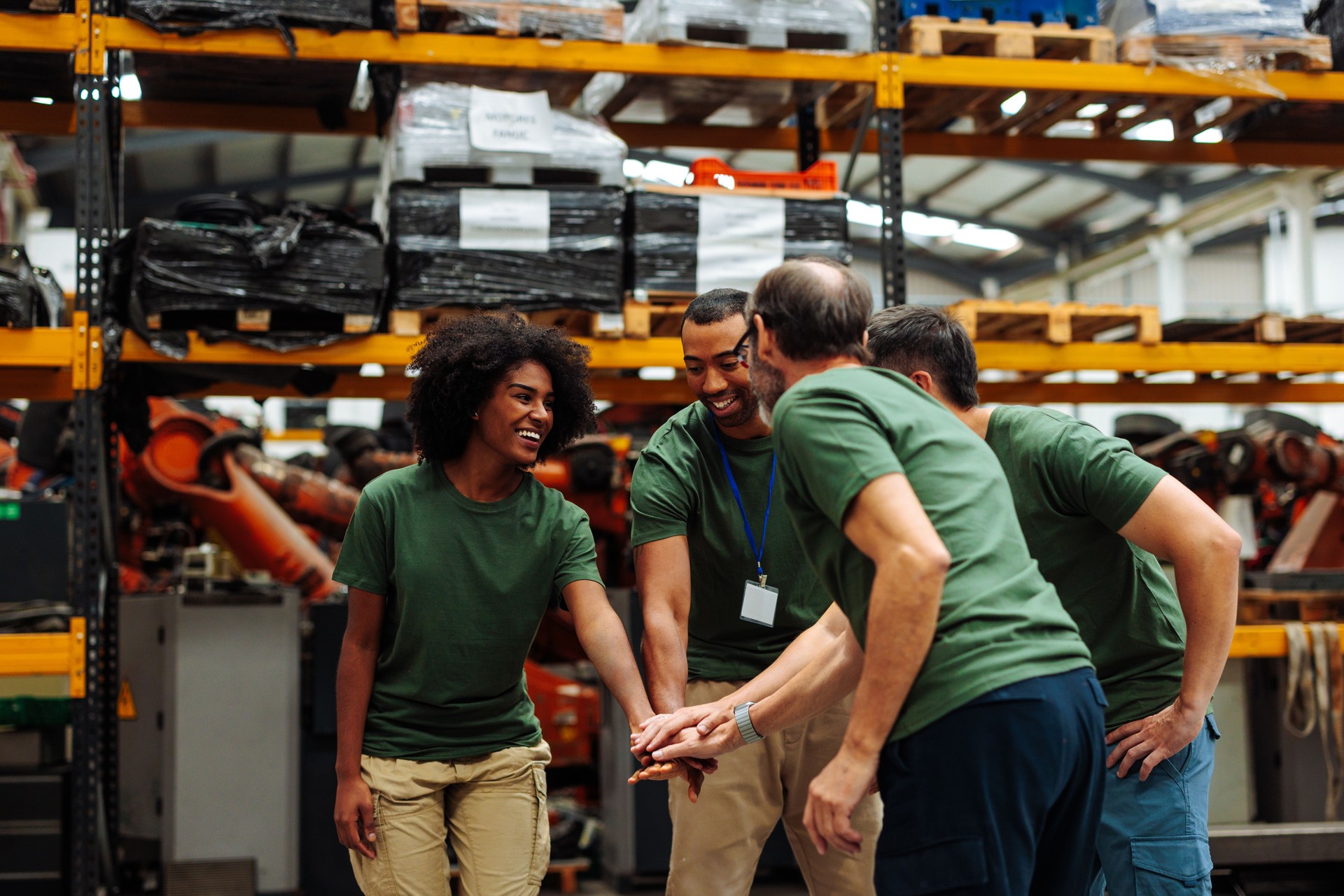 Engineers stacking hands in warehouse, teamwork and collaboration in industrial setting